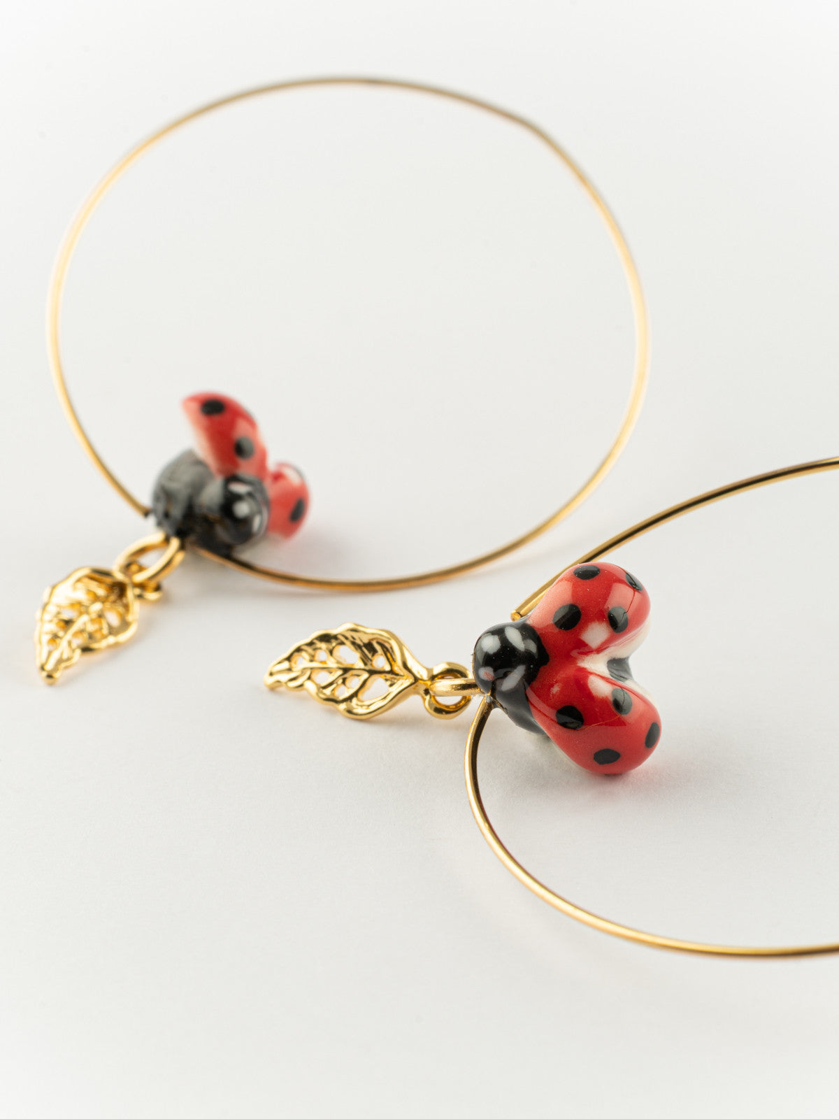 Grandi orecchini a cerchio con motivo a foglia e coccinella